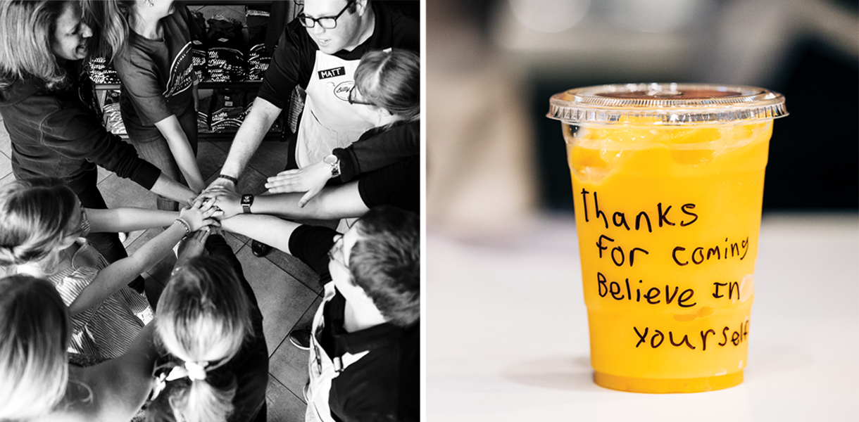 Photographed from overhead, eight employees in a circle join hands in the center. The message, “Thanks for coming. Believe in yourself.” is handwritten on a customer’s plastic cup of orange juice.